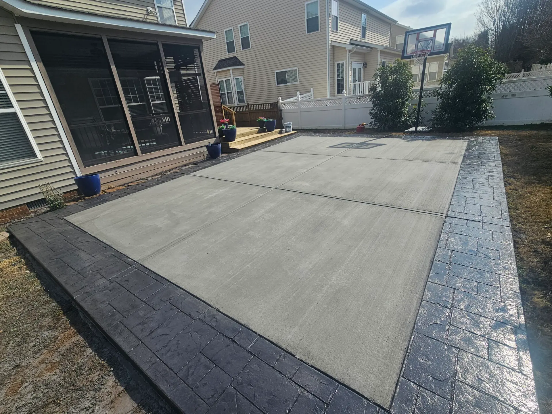Backyard concrete patio with a dark stamped stone border