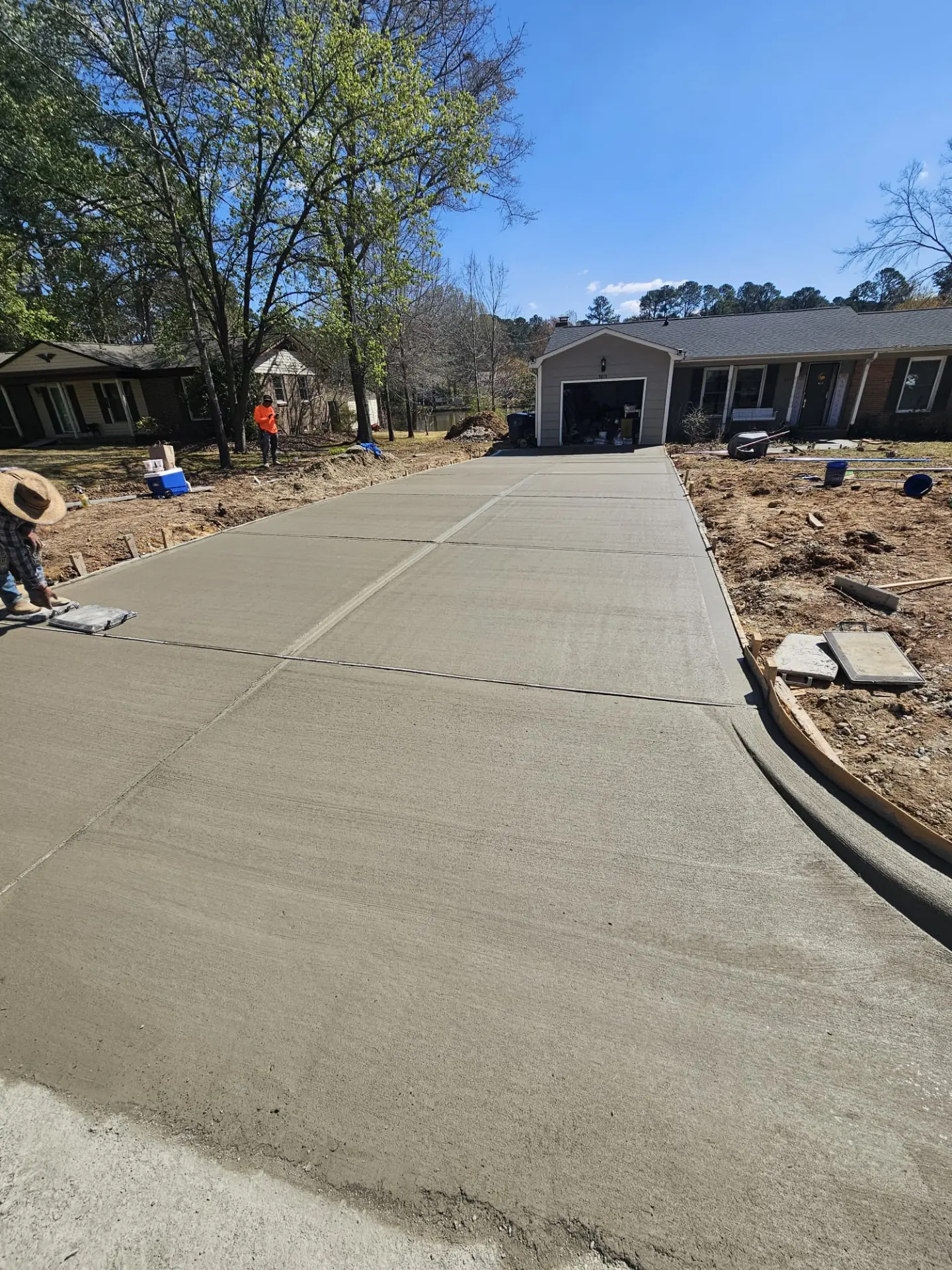 Long broom-finished concrete driveway freshly poured to a two-car garage